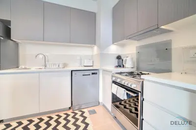 a kitchen with white cabinets and an oven at Graceful 1BR at Park Heights Dubai Hills MBR City by Deluxe Holiday Homes in Dubai