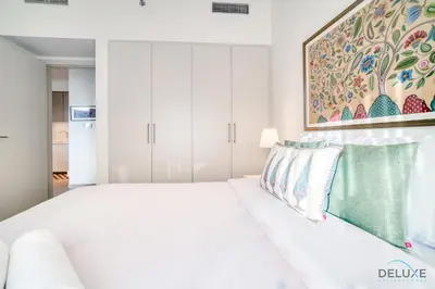 a white bedroom with a white bed and a painting at Graceful 1BR at Park Heights Dubai Hills MBR City by Deluxe Holiday Homes in Dubai