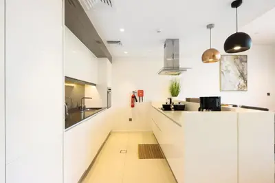 a kitchen with white cabinets and a long hallway at Livbnb - Upgraded 2BR, Near Shopping & Dining Hubs in Dubai