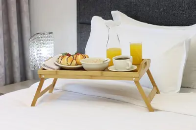 a tray with breakfast foods and juice on a bed at Livbnb - Upgraded 2BR, Near Shopping & Dining Hubs in Dubai