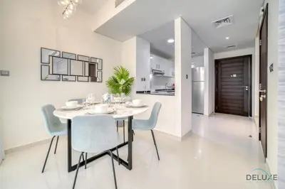 a white dining room with a table and chairs at Cheerful 3BR Townhouse at DAMAC Hills 2, Dubailand by Deluxe Holiday Homes in Dubai