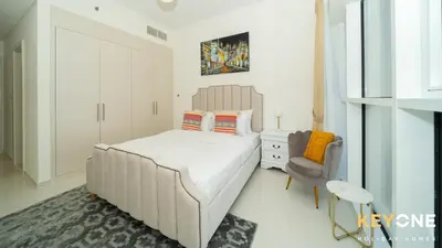 a bedroom with a large bed and a chair at Carson Elegant Living in One Bedroom in Dubai