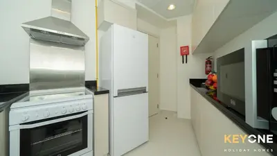 a kitchen with a stove and a refrigerator at Carson Elegant Living in One Bedroom in Dubai