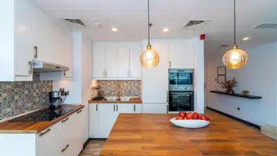 a kitchen with white cabinets and a bowl of fruit on a table at Unique 3BR DUPLEX Apartment with Marina Views in Dubai