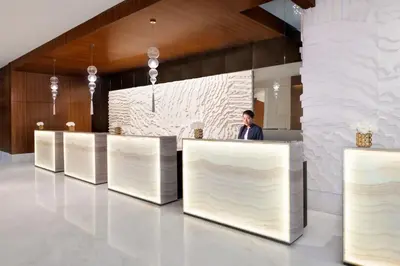a man standing behind a counter in a lobby at Marriott Hotel Al Jaddaf, Dubai in Dubai