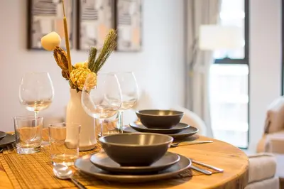 a wooden table with plates and wine glasses on it at Brand new 1 bedroom apartment Dubai Hills 601 in Dubai