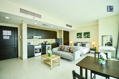 a living room with a couch and a table at Luxury Escapes - Furnished studio with balcony in Royal Oceanic in Dubai