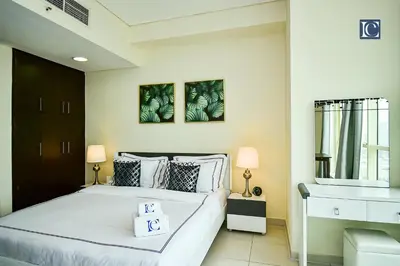 a bedroom with a large white bed with two lamps at Luxury Escapes - Furnished studio with balcony in Royal Oceanic in Dubai