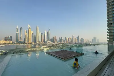 two people swimming in a pool with a city skyline at Tropical Home w Private Beach in Emaar Beachfront in Dubai