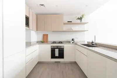 a white kitchen with white cabinets and a sink at Frank Porter - Belgravia 3 in Dubai
