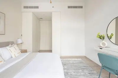 a white bedroom with a bed and a mirror at Frank Porter - Belgravia 3 in Dubai
