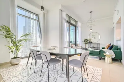 a dining room and living room with a table and chairs at Burj Vista, Downtown Dubai - Burj Khalifa View - Mint Stay in Dubai