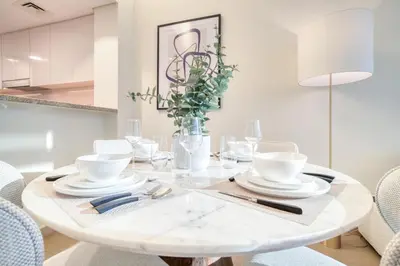 a white dining room with a white table and chairs at Burj Vista, Downtown Dubai - Burj Khalifa View - Mint Stay in Dubai