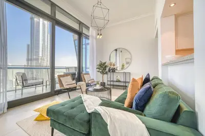 a living room with a green couch and large windows at Burj Vista, Downtown Dubai - Burj Khalifa View - Mint Stay in Dubai