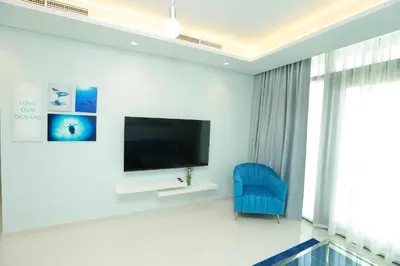 a living room with a tv and a blue chair at Paramount Midtown - Fantastic 2 Bedroom Apartment with Sea View in Dubai