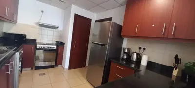 a kitchen with wooden cabinets and a stainless steel refrigerator at Spacious 2 BR with Amazing Marina View Rimal JBR in Dubai
