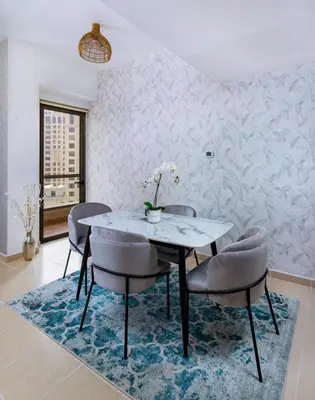 a dining room with a table and chairs on a rug at Spacious 2 BR with Amazing Marina View Rimal JBR in Dubai