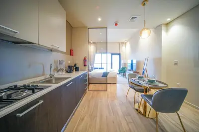 a kitchen and living room with a table and chairs at Big Modern Studio in Park View JVC in Dubai
