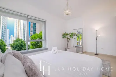 a white bedroom with a large bed and a window at LUX - The Downtown Blvd Suite in Dubai