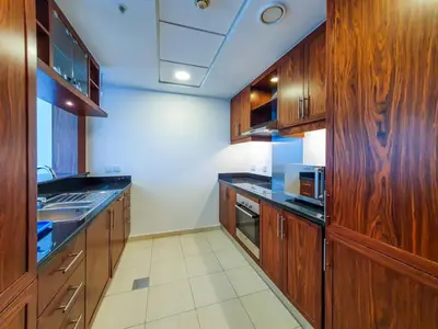 a large kitchen with wooden cabinets and a microwave at The Residence 7 Downtown - Full Burj Khalifa and Fountain Views by Gardenia Suites in Dubai