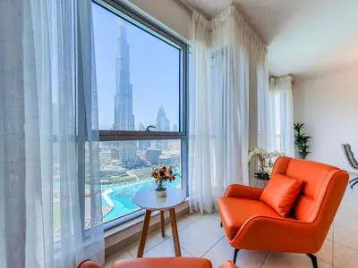 an orange chair in a room with a large window at The Residence 7 Downtown - Full Burj Khalifa and Fountain Views by Gardenia Suites in Dubai