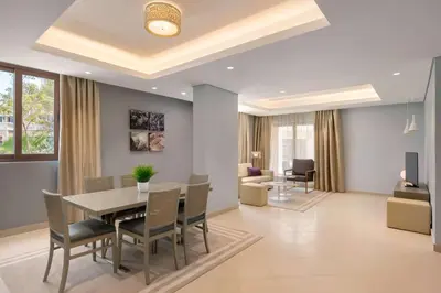 a dining room and living room with a table and chairs at Wyndham Residences The Palm in Dubai