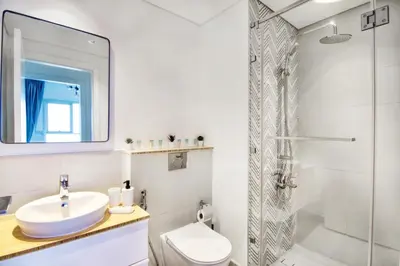a white bathroom with a sink and a shower at GuestReady - In the Heart of Dubai Hills in Dubai