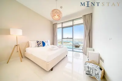 a white bedroom with a bed and a large window at Beach Vista 1 Emaar Beachfront - Mint Stay in Dubai