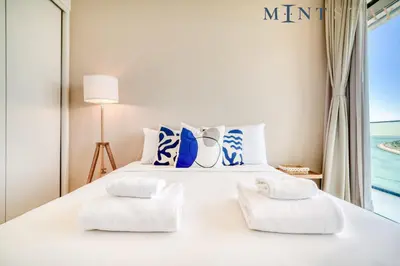 a white bed with white pillows and a window at Beach Vista 1 Emaar Beachfront - Mint Stay in Dubai
