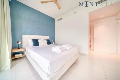 a bedroom with a white bed and a blue wall at Beach Vista 1 Emaar Beachfront - Mint Stay in Dubai
