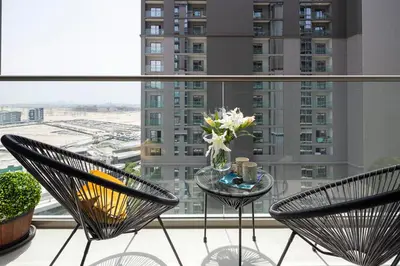a balcony with two chairs and a glass table with flowers at Frank Porter - Sobha Creek Tower B in Dubai