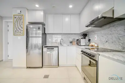 a kitchen with white cabinets and a stainless steel refrigerator at Exclusive Deal Stunning 1BR at Madinat Jumeirah by Deluxe Holiday Homes in Dubai