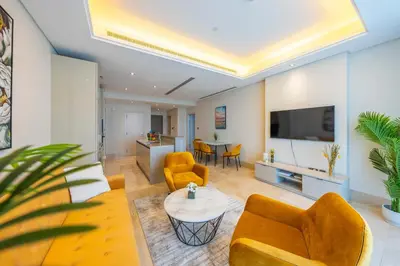 a living room with yellow furniture and a tv at Spacious beachfront 2 bedroom apartment - The 8 in Dubai