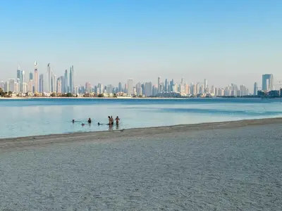 a group of people in the water at a beach with a city at Spacious beachfront 2 bedroom apartment - The 8 in Dubai