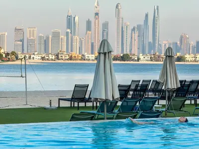a person in a swimming pool with chairs and umbrellas at Spacious beachfront 2 bedroom apartment - The 8 in Dubai