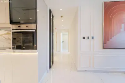 a white hallway with a television and a fireplace at JBR Amwaj 4 , Upgraded Sea and Ain Dubai Views, 2m walk to Beach By Gardenia Suitse in Dubai