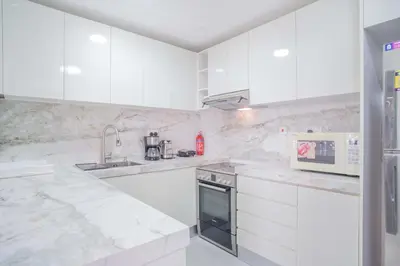 a white kitchen with white cabinets and a microwave at JBR Amwaj 4 , Upgraded Sea and Ain Dubai Views, 2m walk to Beach By Gardenia Suitse in Dubai