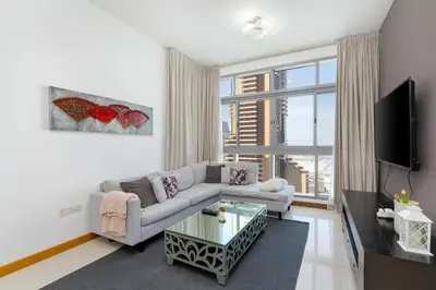 a living room with a couch and a tv at Vacay Lettings - 2BHK with Dubai Marina View in Dubai