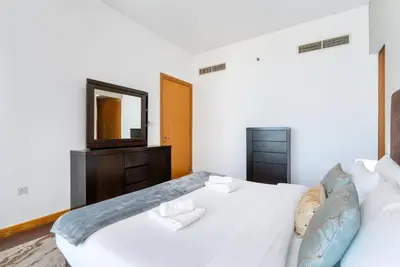 a bedroom with a white bed and a mirror at Vacay Lettings - 2BHK with Dubai Marina View in Dubai