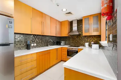 a kitchen with wooden cabinets and white counter tops at Vacay Lettings - 2BHK with Dubai Marina View in Dubai