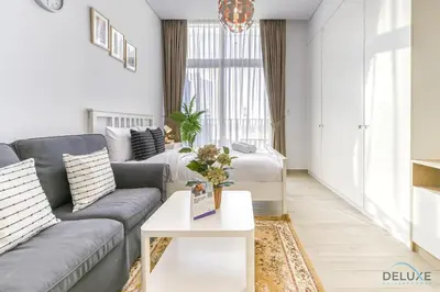 a living room with a couch and a table at Cheerful Studio at Belgravia Tower JVC by Deluxe Holiday homes in Dubai