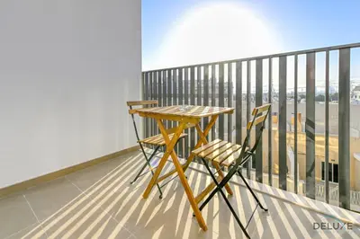 a wooden table and chair on a balcony with a view at Cheerful Studio at Belgravia Tower JVC by Deluxe Holiday homes in Dubai