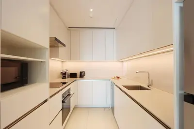 a white kitchen with white cabinets and a sink at Prime 1BR with Marina Views and Beach Access in Dubai