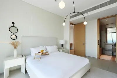 a white bedroom with a white bed and a table at Prime 1BR with Marina Views and Beach Access in Dubai