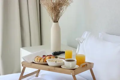 a tray of breakfast food on a bed with orange juice at Prime 1BR with Marina Views and Beach Access in Dubai