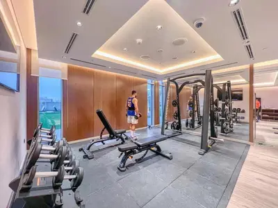 a gym with several treadmills and a man standing in the middle at White Sage - Elegant Apartment With Unobstructed City Views in Dubai