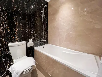 a bathroom with a white toilet and a bath tub at Luton Vacation Homes - Elite Downtown Residence, Burj Khalifa View Dubai - 19AB01 in Dubai