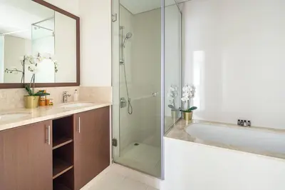 a bathroom with a glass shower and a tub at Frank Porter - Boulevard Crescent in Dubai