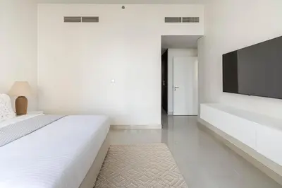 a white bedroom with a large bed and a flat screen tv at Frank Porter - Boulevard Crescent in Dubai