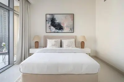 a white bedroom with a large white bed with two lamps at Frank Porter - Boulevard Crescent in Dubai